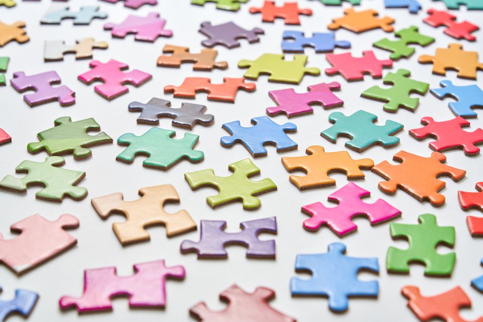 Vibrant jigsaw puzzle pieces scattered on a white background in a still life composition.