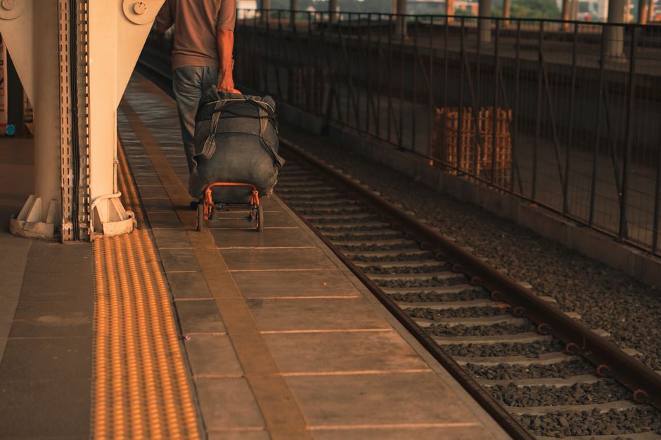 A person with luggage waiting on a platform at an urban train station, highlighting travel and transit.